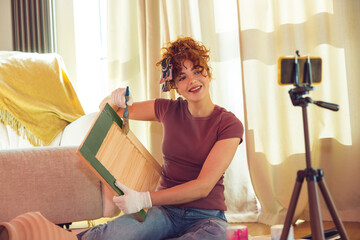 Smiling young artist showing her wood painting online