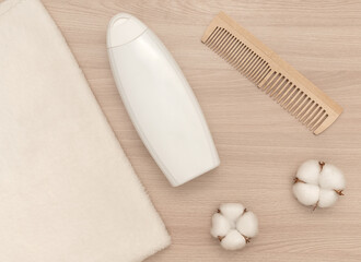 Fototapeta na wymiar White towel and white shampoo and wooden comb white cotton flowers.