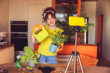 Woman in yellow planting and watering home plants