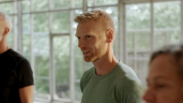 Group of people talking together while standing in a studio before a yoga class