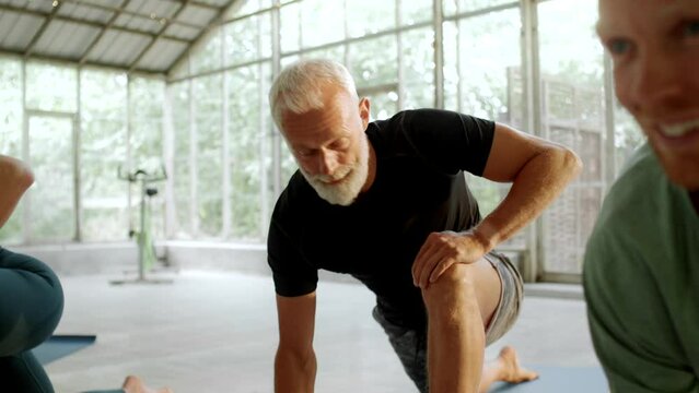 Fit mature man doing stretching exercises before a class in a yoga studio
