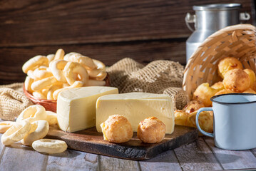 Cheese bread and more, cheese bread, manioc flour cookies and Minas cheese arranged on a rustic wooden surface with accessories, selective focus.