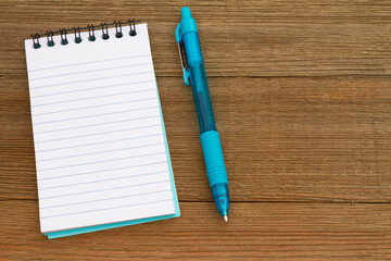 Teal notepad and pen on weathered wood