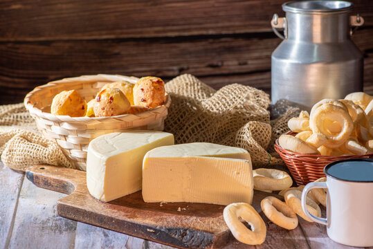 Cheese bread and more, cheese bread, manioc flour cookies and Minas cheese arranged on a rustic wooden surface with accessories, selective focus.