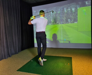 Male golfer playing golf in vr headset. Golf simulator indoor