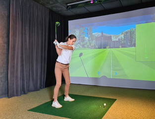 Female golfer plays golf on golf simulator