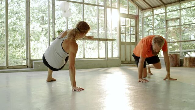 Smiling female instructor teaching yoga to a class in her studio
