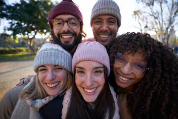 Multiethnic group of people taking selfie outdoors looking at camera cheerfully.