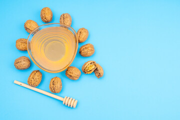 Walnuts with honey. Festive blue background, transparent bowl with honey and walnuts.