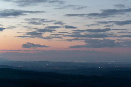 Light spots in dark countryside at twilight, hilly landscape and cloudy sky