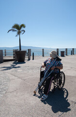 beautiful young amputee woman with crutches sitting on a wheelchair on the beach