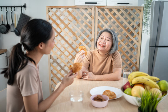 Asian senior mother having breakfast and talking with daughter at the tablet. Asia family enjoy eating together.