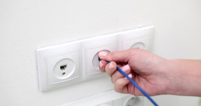 Closeup of woman hand inserting network cable into wall socket