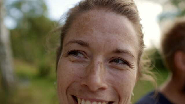Woman laughing while enjoying an outdoor lunch with family and friends in summer