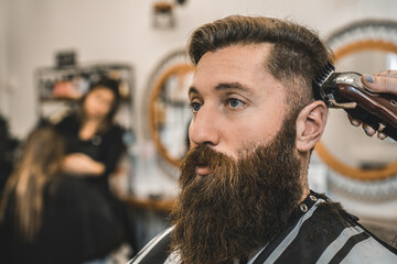 Hipster man at barbershop for beard and hair cutting - Female hands of hairdresser woman using hair clipper for classic gentleman cut - Barber shop concept