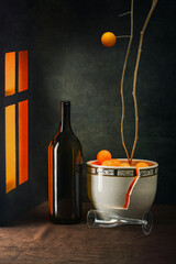 Still life with a bottle by the window and a broken vase with a plant