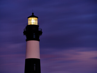 The amazingly stunning Bodie Island Lighthouse on the Outer Banks of North Carolina shines its beacon out to sea at sunset