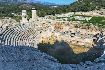 Naklejka premium Amazing view of theatre of Xanthos ancient city - part of Lycian way. Tomb monument of king Kybernis ( Harpy Tomb), Pillar Tomb on background. Popular travel destination in Antalya, Turkey