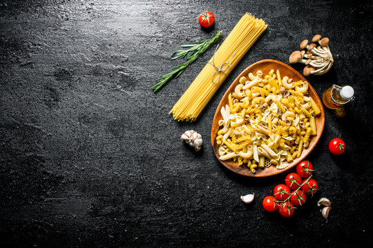 Raw pasta assortment with rosemary,tomatoes and mushrooms.