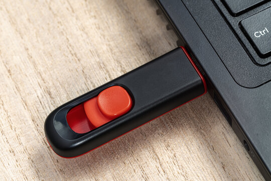 Black and red USB flash stick inserted to laptop computer's USB port