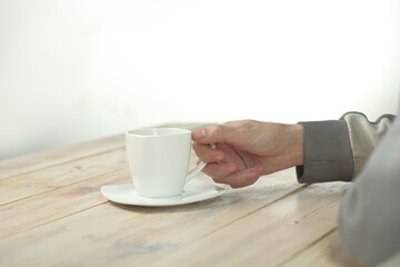 a person holding a cup with coffee in his hand on a table made of boards