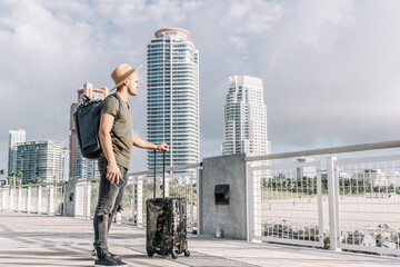 Side view Young Man Standing With Suitcase and enjoying the view before departure