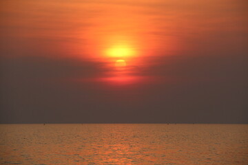 A stunning sunset over the calm sea cover by the orange sunlight.