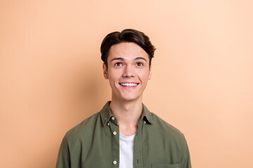 Obraz premium Portrait of nice cheerful man beaming smile look up empty space information isolated on beige color background