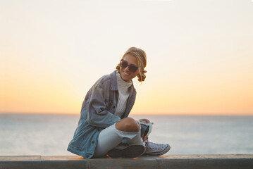 Happy young female enjoying the sunset. Cheerful and happy. Hipster girl by the sea in sunset light.