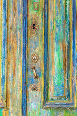 Fototapeta na wymiar Keyhole on an old door covered with many layers of colorful paint