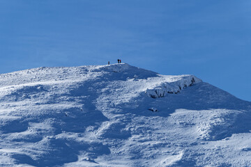 Mountaineers on the top of the mountain on a winter sunny day. Hiking in the winter. Travel and free spirit feeling. 