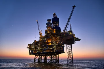 Selbstklebende Fototapeten Offshore oil and gas platform in the sea at sunset. Jack up rig crude oil production in ocean. © Igor Hotinsky