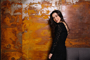 Fototapeta premium lovely cute elegant young woman in festive black dress posing at camera. Charming girl with wonderful smile. miling woman hairstyle wavy curls . Fashion , beauty and makeup portrait