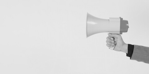The man's hand is holding a megaphone and wears a grey suit on white background.