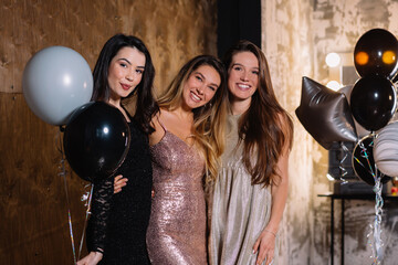 Close up portrait of three young women dressed festive dresses smiling at camera. Adorable happy...