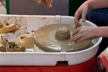 Making A Clay Pot. Potter working on potters wheel making ceramic pot from clay in pottery workshop on outdoor at November in shadow of building. Creative workshop and masterclass.