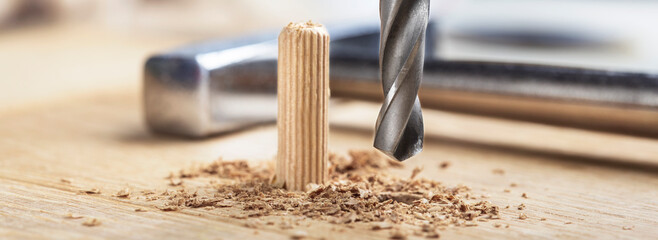 drill bit makes hole in wooden oak board for wooden dowel.