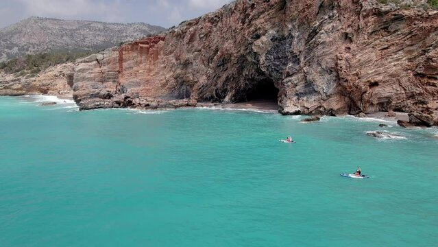 Aerial view of family supboarding down azure sea