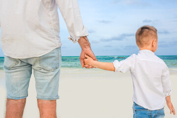 Fototapeta premium Father holding son's hand at the beach