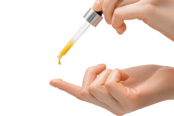 A pipette of orange-colored serum drips on the finger of a woman's hand, on a light background, close-up.