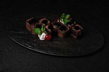 Dessert of Asian cuisine - sweet sushi roll in chocolate crepe with chocolate sauce