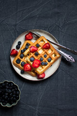 Traditional belgian waffles with fresh berries on dark background