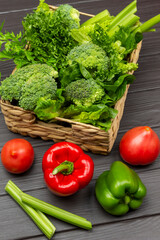  Tomatoes and peppers on the table. Lettuce, broccoli and celery stalks in a wicker basket.