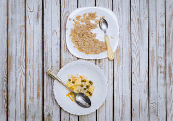 Leftovers from soup, porridge, uneaten food lies on plates after a person on a wooden table. Photography, concept, wooden background.