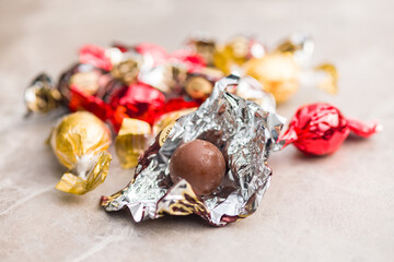 Sweet chocolate candy wrapped in foil on kitchen table.