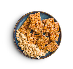 Sweet peanut brittle on plate. Tasty peanuts in caramel isolated on white background.