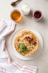 Stack of homemade pancakes served with honey and berries, top view