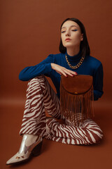 Fashionable confident woman wearing stylish blue turtleneck, trendy flared trousers with zebra...