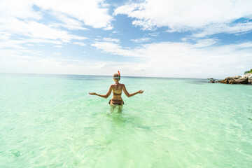 Woman in a brown bikini snorkeling on Maldives. Back view. Tropical coastline. Tourist. Traveler. Hobby. Wanderlust