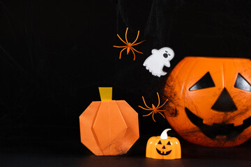 Orange pumpkins, a ghost, spiders and spider webs on a black background, a Halloween banner copy space for text.